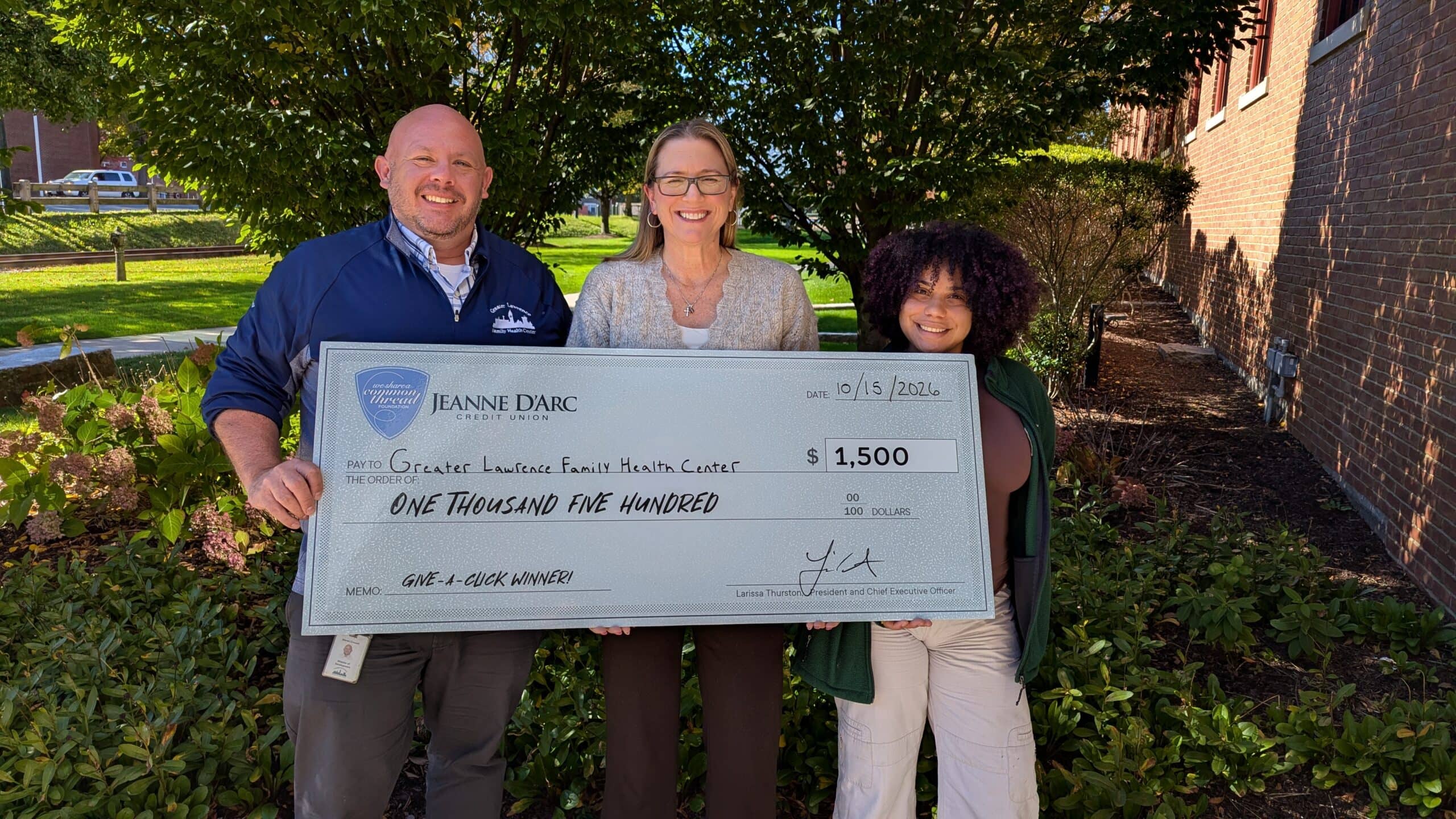 (left to right) Steven Crowell, Director, Development & Marketing and Sonja Then, Manager of Marketing and Communication and Development Associate from Greater Lawrence Family Health Center accept a $1,500 check from Alison Hughes, Vice President, Community Engagement (center) of Jeanne D’Arc Credit Union for being the Q3 2026 winner of the Give-A-Click campaign on October 15, 2026.