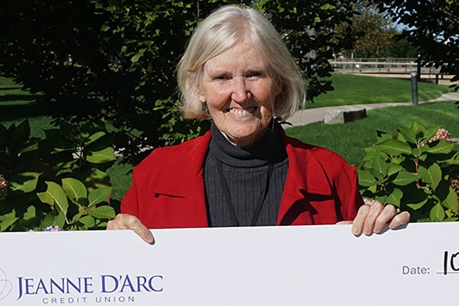 Elizabeth Kidd holding a check from Jeanne D'Arc Credit Union