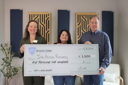 Larissa Thurston, President and CEO of Jeanne D’Arc Credit Union, presents a check for $1,500 to Into Action Recovery Vice President, Mary-Ellen Cooper, and Into Action Recovery board member Steve Goodell.