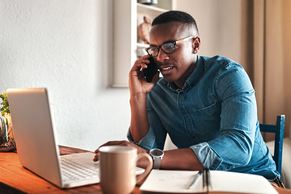 A man on his cell phone looking at his laptop