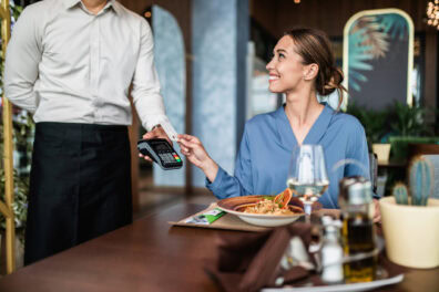 A woman pays for a meal at a restaurant with her credit card.