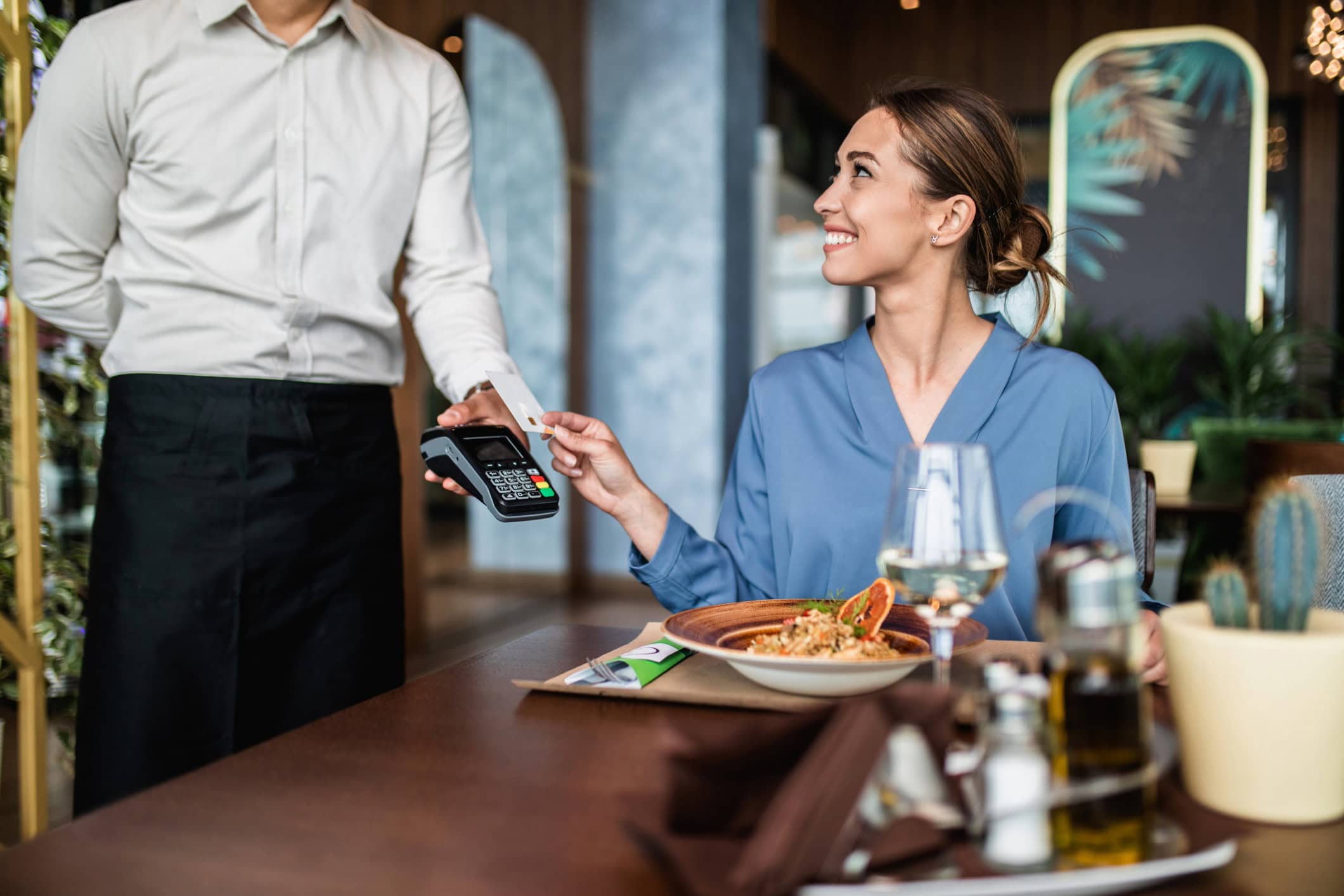 A woman pays for a meal at a restaurant with her credit card.