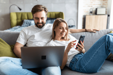 A couple relaxes on their couch in their studio apartment.