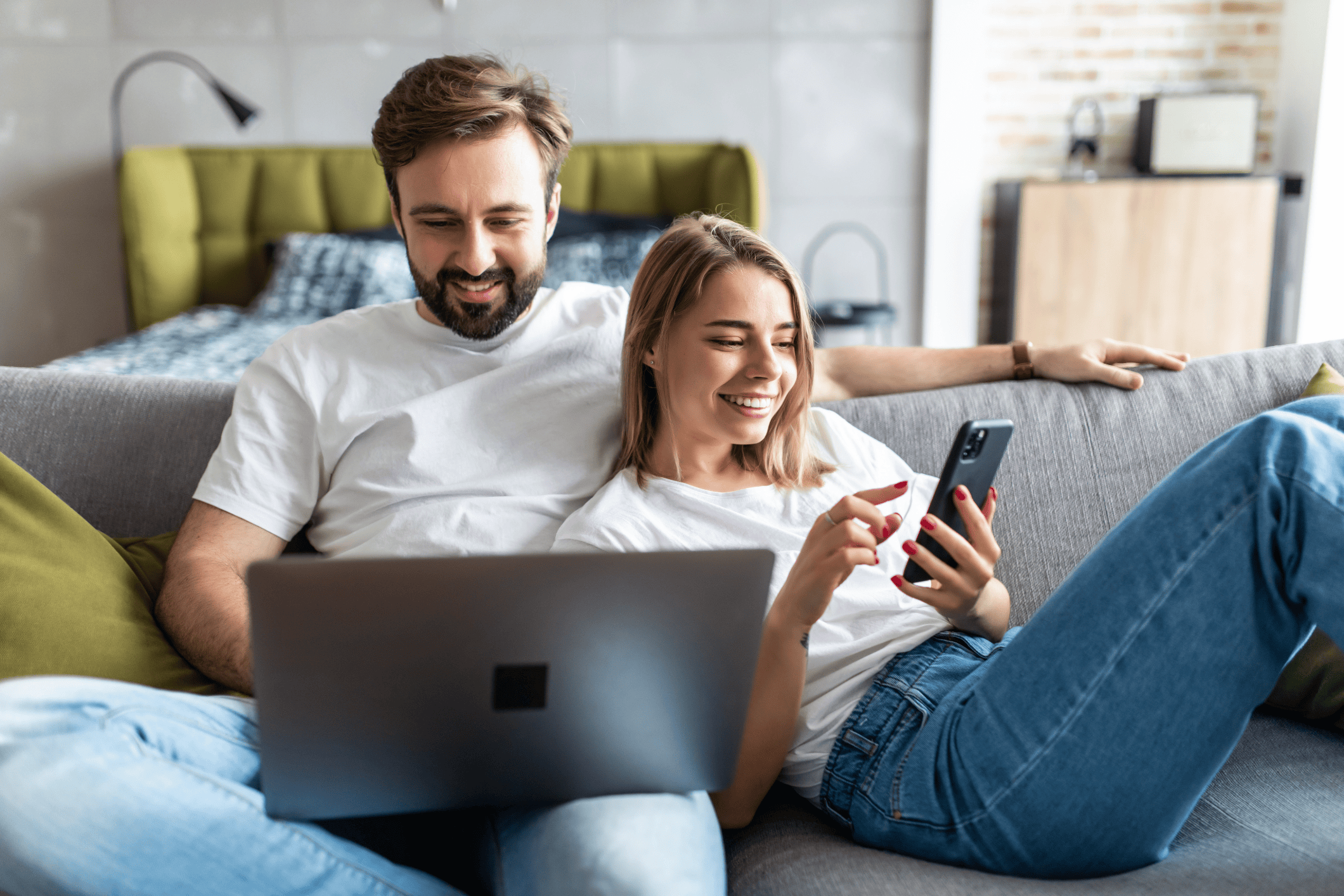A couple relaxes on their couch in their studio apartment.