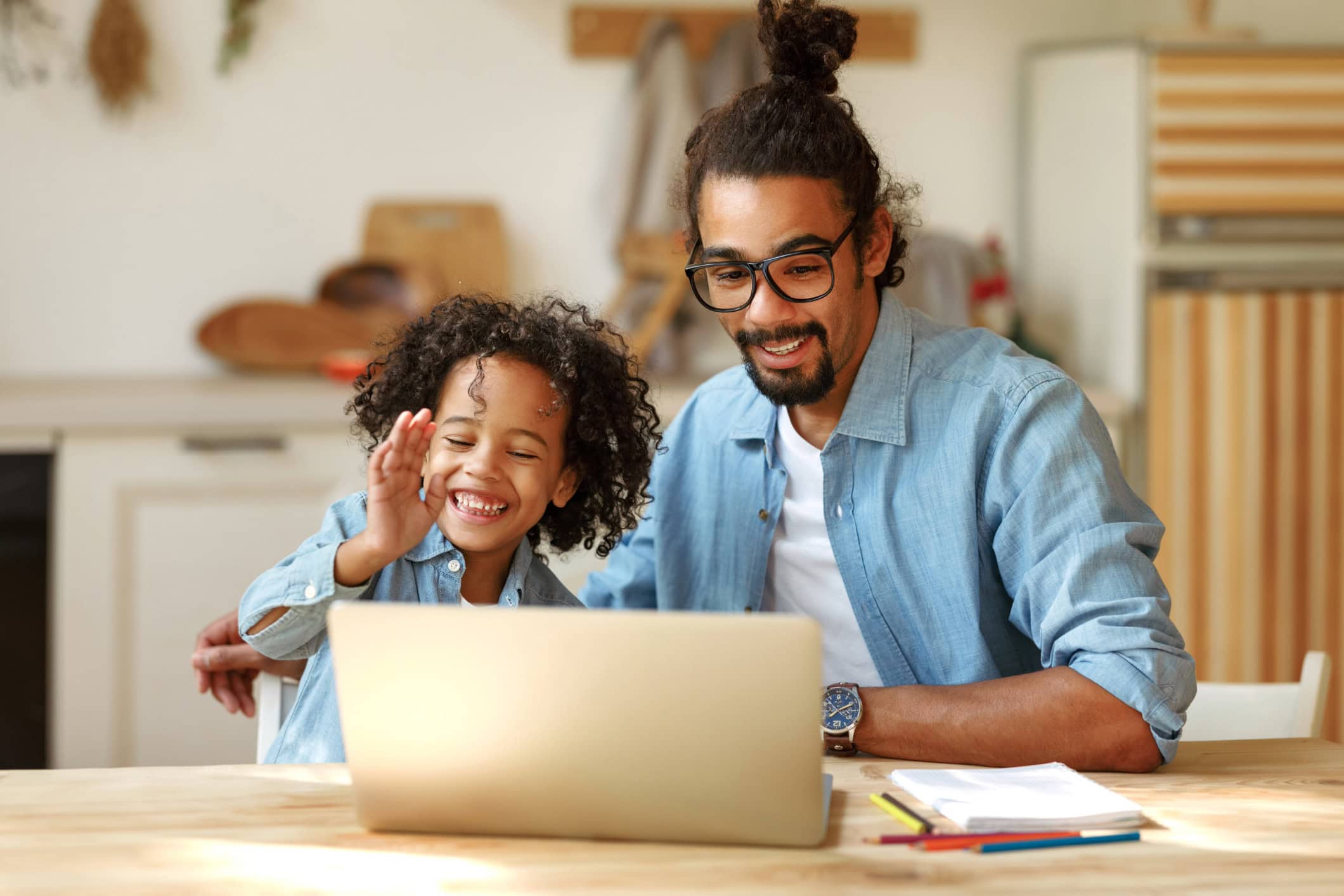 Happy Black father and son enjoying video call on laptop at home