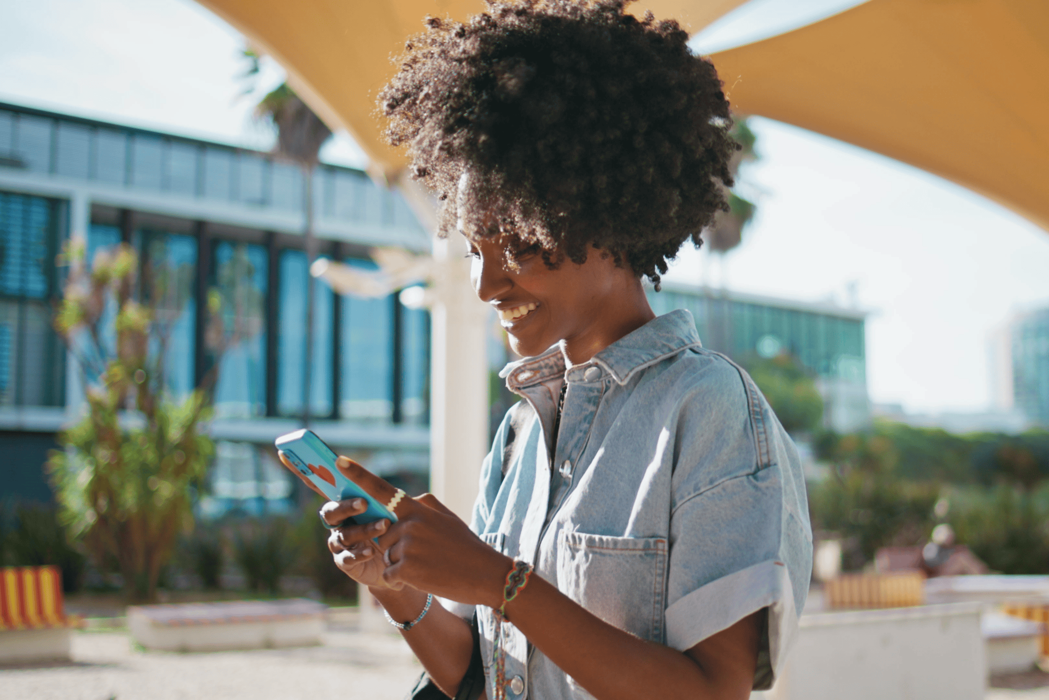 A Black woman with natural hair looks at her cell phone.