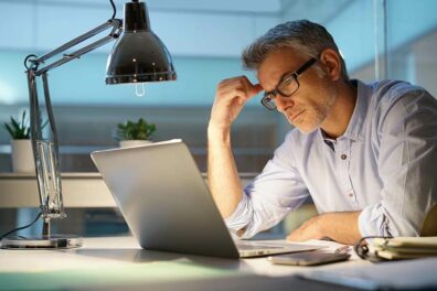 A serious man does research on his laptop about the best way to consolidate debt without hurting credit.