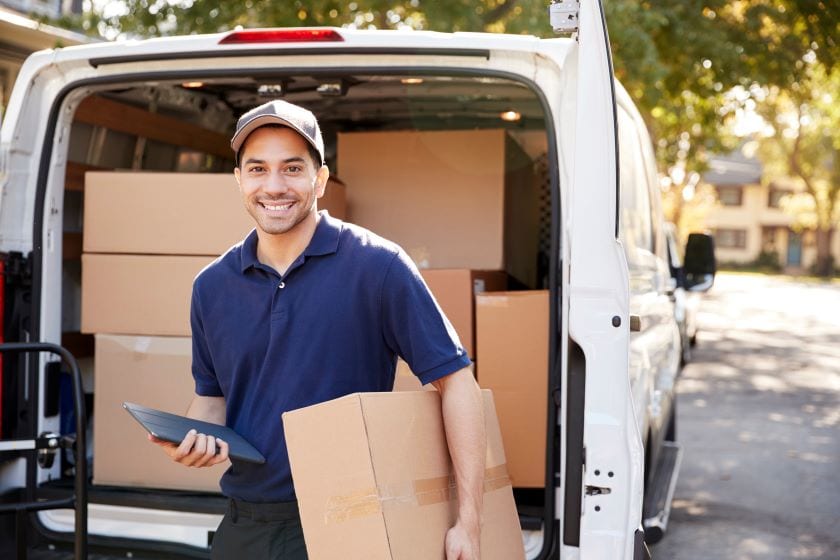 A man delivers a package using a small commercial van