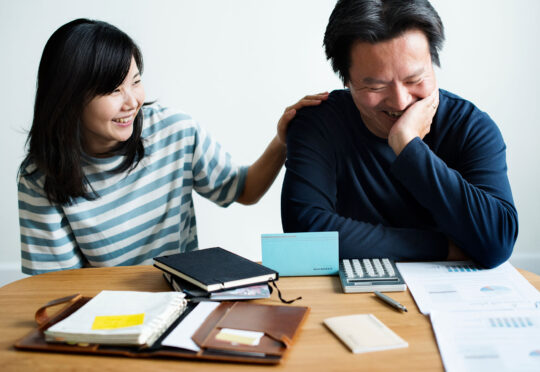 A happy couple reviews their finances to discover that their financial wellness plan is working.