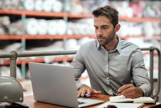 A warehouse manager checks order on his laptop computer.