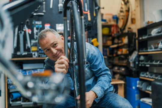 A bicycle mechanic works in his shop with equipment funded with a term business loan.