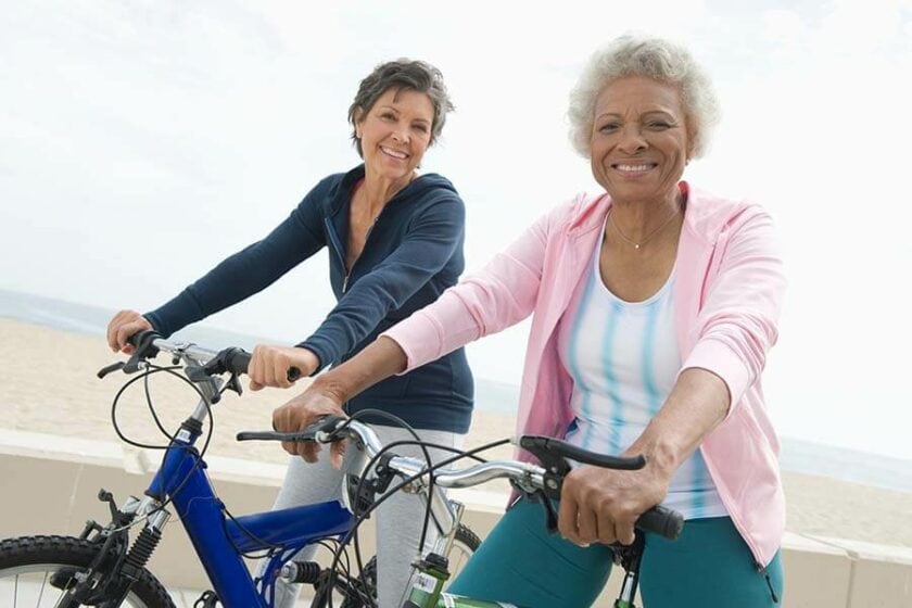 Two older women ride bikes and enjoy their retirement thanks to a Roth IRA.