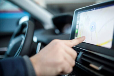 Closeup of a person using the navigation screen of their rental car.