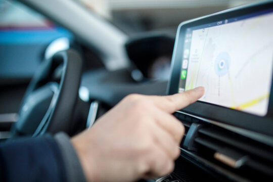 Closeup of a person using the navigation screen of their rental car.