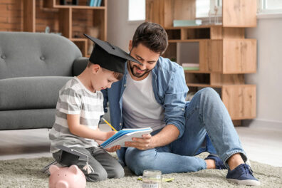 A father and young son sitting on floor counting piggy bank money that will be used for an education savings account.