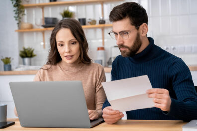 A couple doing research on a laptop about how debt consolidation works.