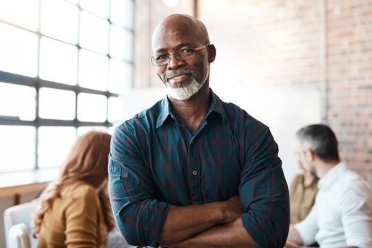 A confident businessman sits in a sunny boardroom
