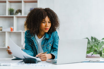 Woman at laptop researching money markets vs. CDs as investment opportunities.