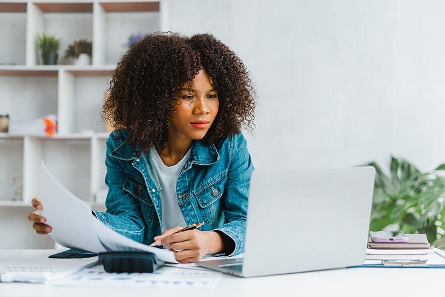 Woman at laptop researching money markets vs. CDs as investment opportunities.