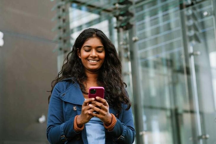 A young woman applying for a personal loan for debt consolidation using her phone.