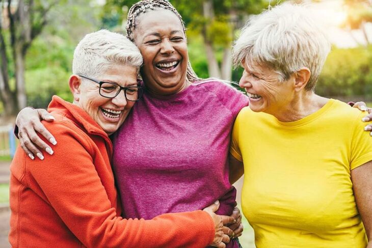 Three Jeanne D'Arc Credit Union ladies share a laugh and a hug at the local park before their yoga class.