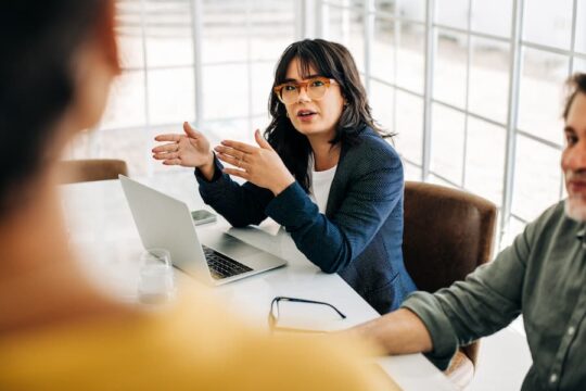 A manager explains strategy to her team during a meeting in an office