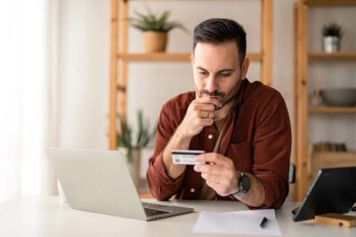 A man with heavy credit card debt does online research about credit card refinancing vs. debt consolidation to determine which is better for him.