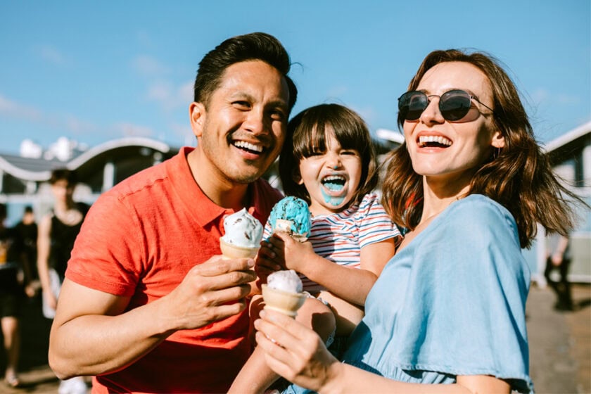 A family of three eating ice cream while on vacation.