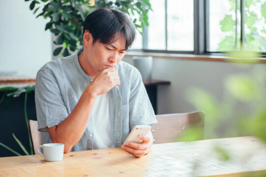 A man feeling down while looking at his smartphone.