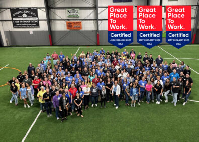 Group picture of Jeanne D'Arc employees with three Great Place to Work badges in the upper right corner of the image.