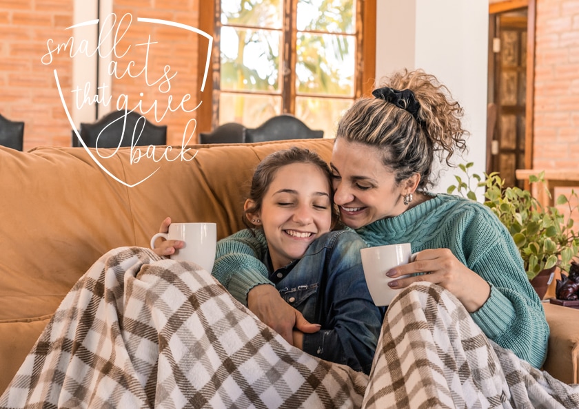 Mother and daughter having hot drink on the sofa in the living room