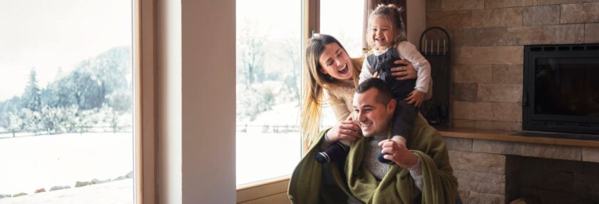 Young family on winter vacation, looking through window