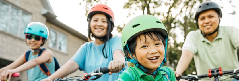 Family of four riding bikes in their neighborhood.