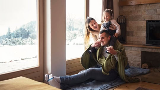 Young family on winter vacation, looking through window