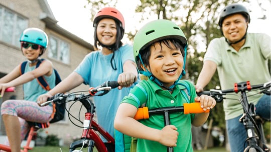 Family of four riding bikes in their neighborhood.