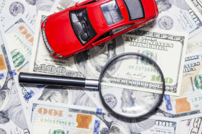 a magnifying glass, a stack of money, and a car