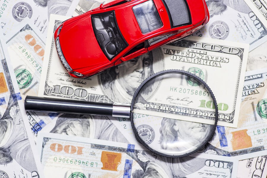 a magnifying glass, a stack of money, and a car