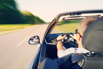 a man driving his convertible on an open road