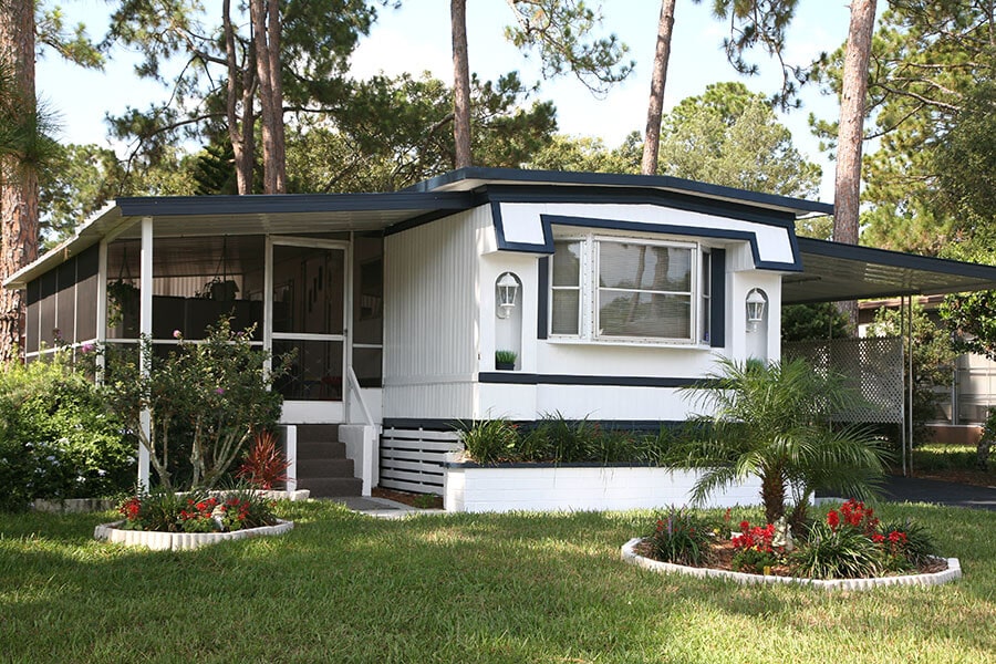 exterior view of a mobile home with lush landscaping