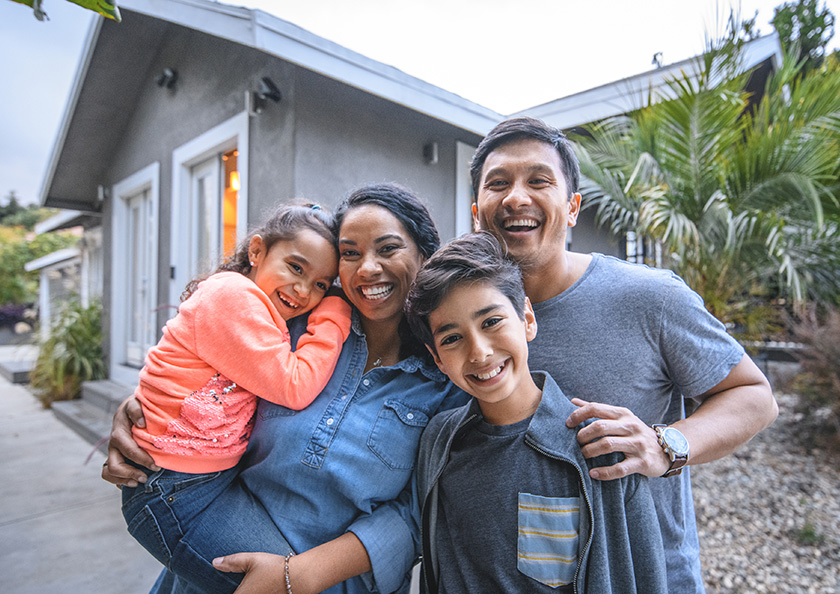A family standing together in front of a home