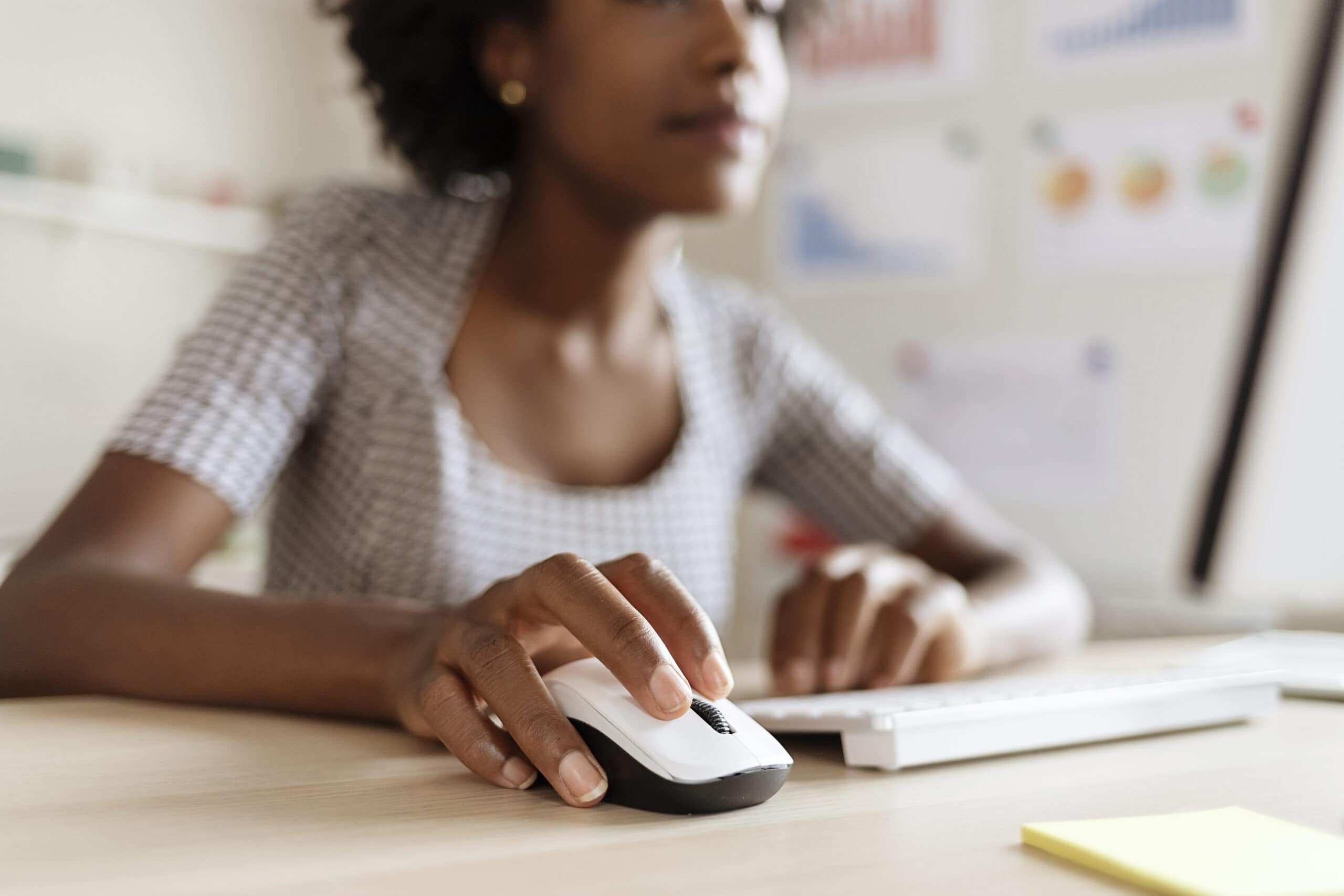 Closeup of a Black woman's hand as she uses a computer mouse.