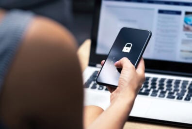 A closeup of a person holding a smartphone. The smartphone has a lock symbol on it.