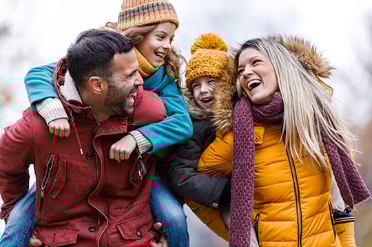 Young cheerful family having fun while piggybacking in autumn day at the park.