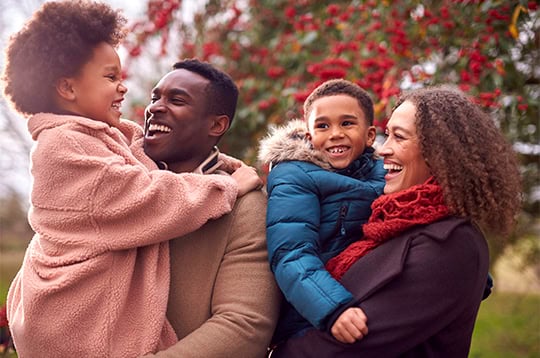 Parents Carrying Children As Family Enjoy Fall