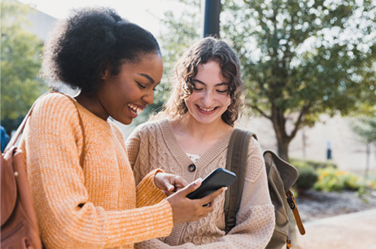 Teen girl shows friend something on her smart phone