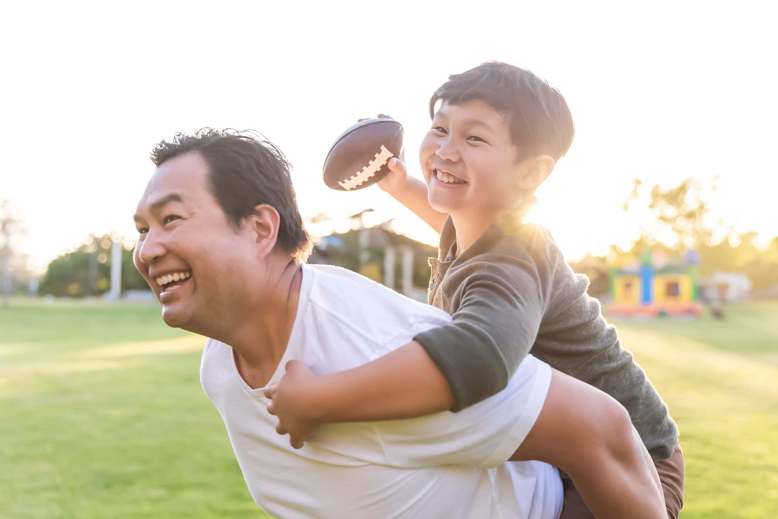 Father and son play football in a park