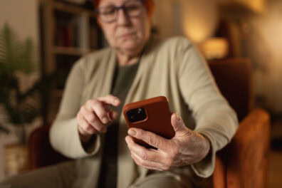 Senior woman ready to answer a phone call on her cell phone. Her right index finger is pointed, ready to pick up the call.