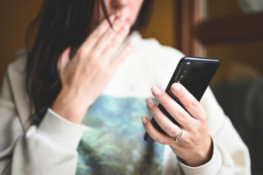 Woman looking anxiously at her cell phone.