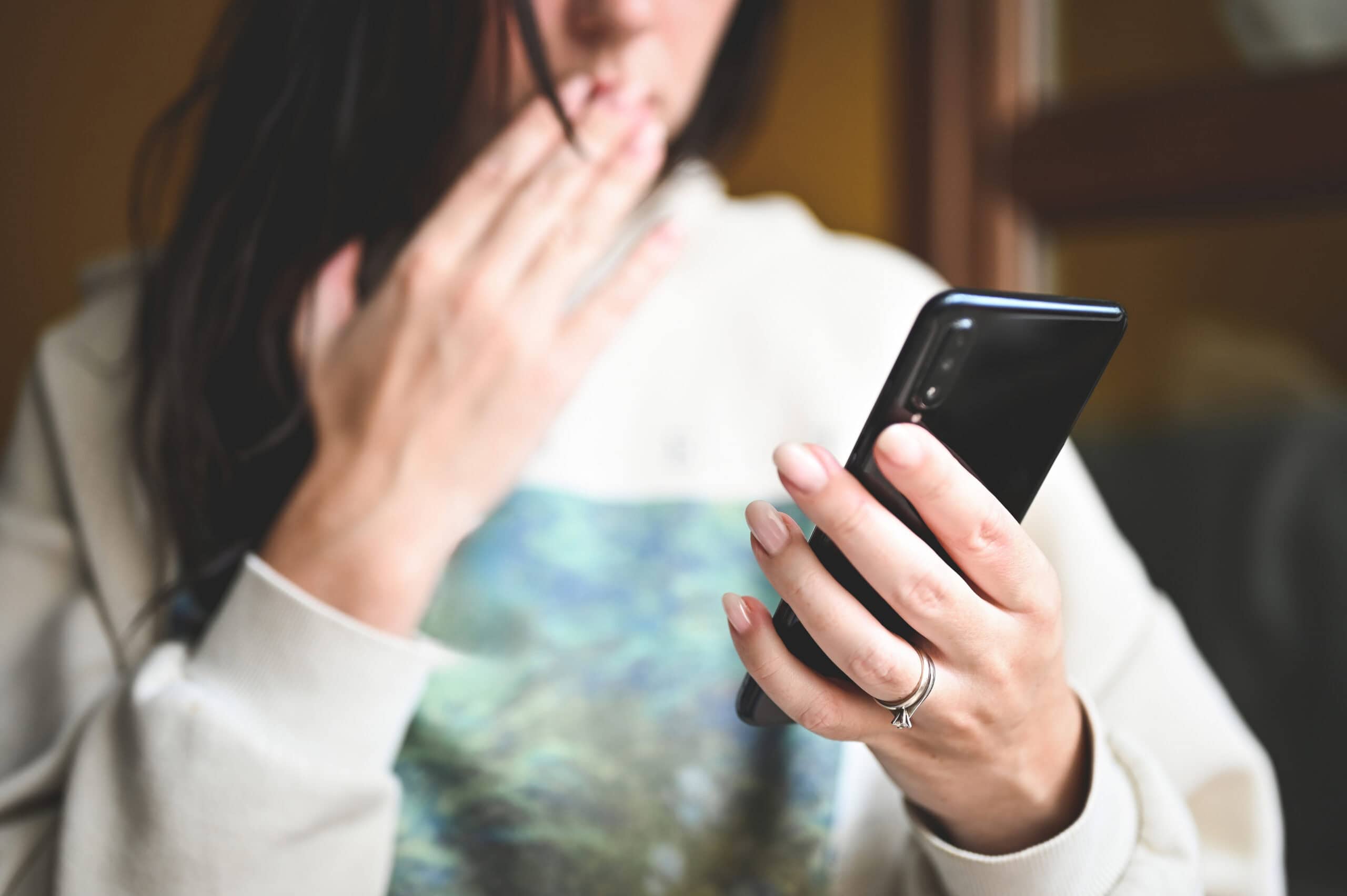 Woman looking anxiously at her cell phone.