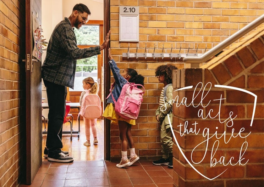 Teachers high fiving elementary school students as they enter the classroom.